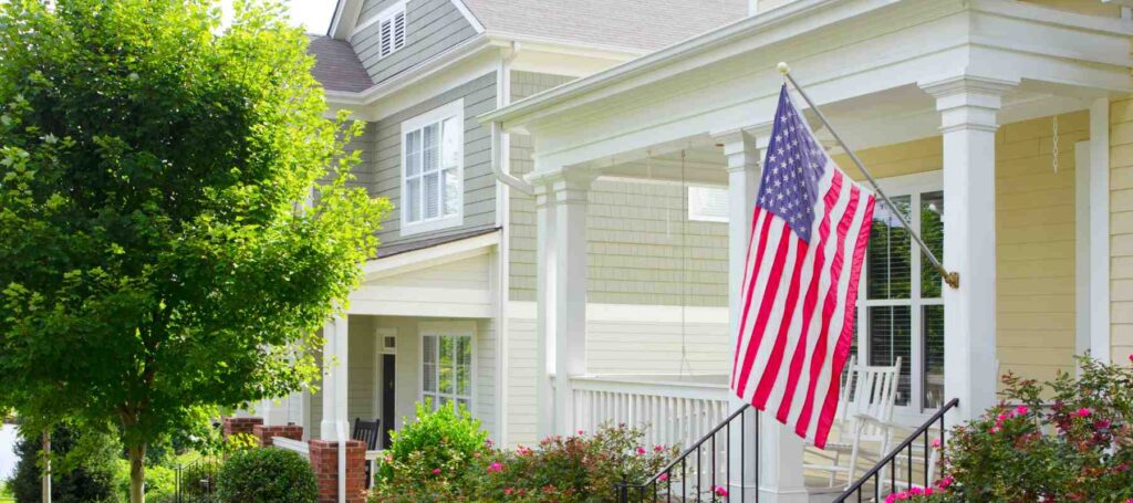 An American flag is displayed on the front porch of a home
